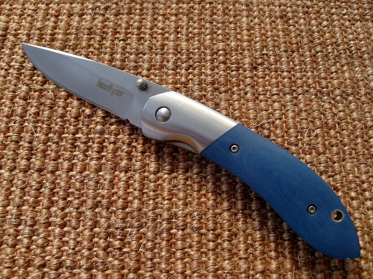 a large blue knife is laying on a fabric