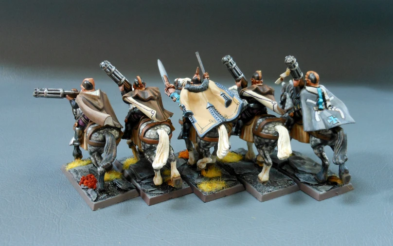 four miniature model soldiers and a warhammer