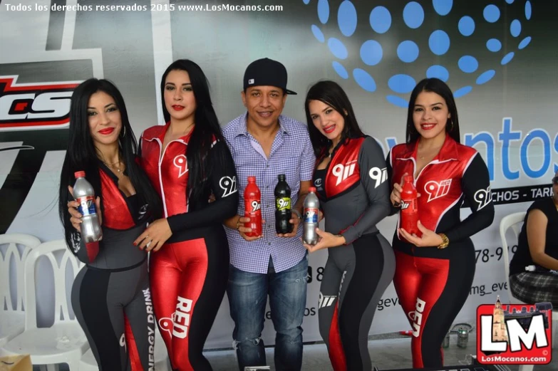 a man is posing with a group of girls in red and gray outfits