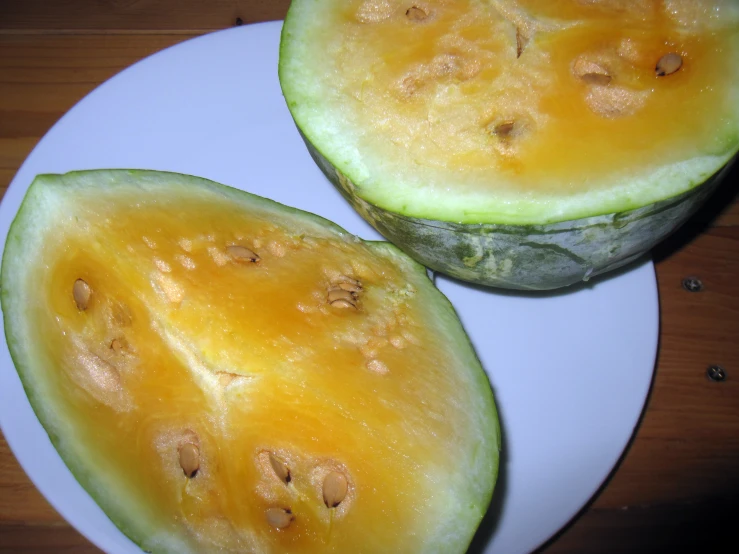 two yellow fruits that are on a white plate