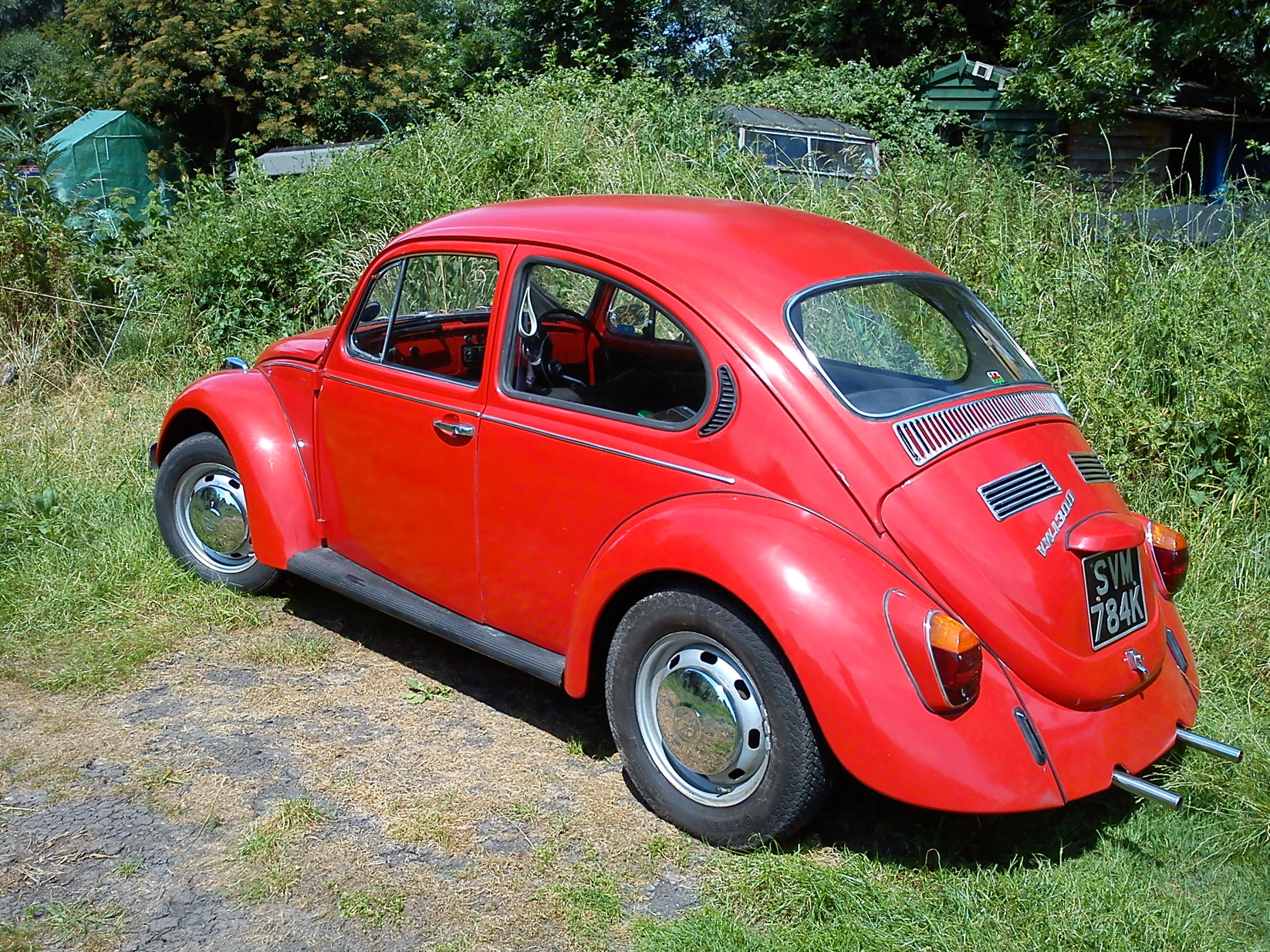 a red car parked next to green grass