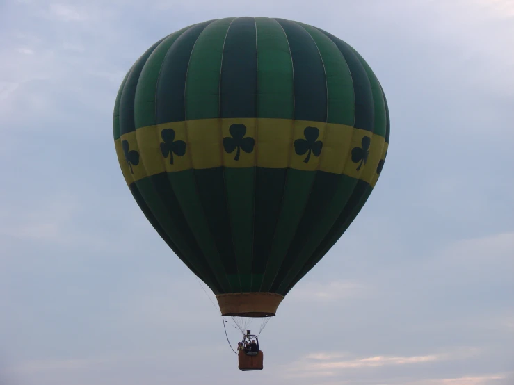 a green and yellow balloon flying in the sky