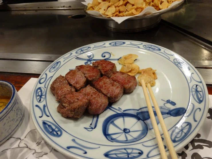 a close - up of the meat on the plate with chopsticks