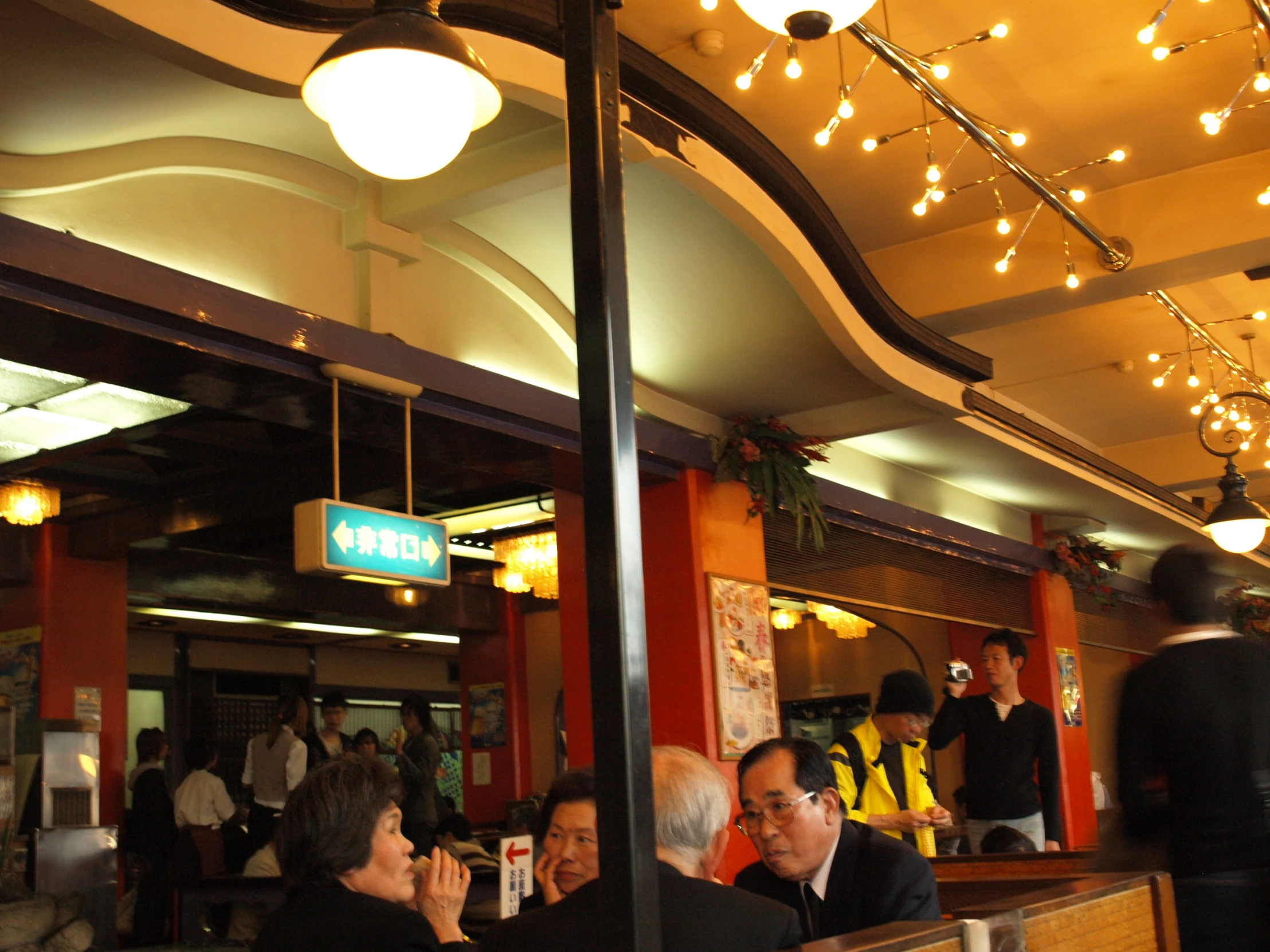 group of people eating at table with lights above them