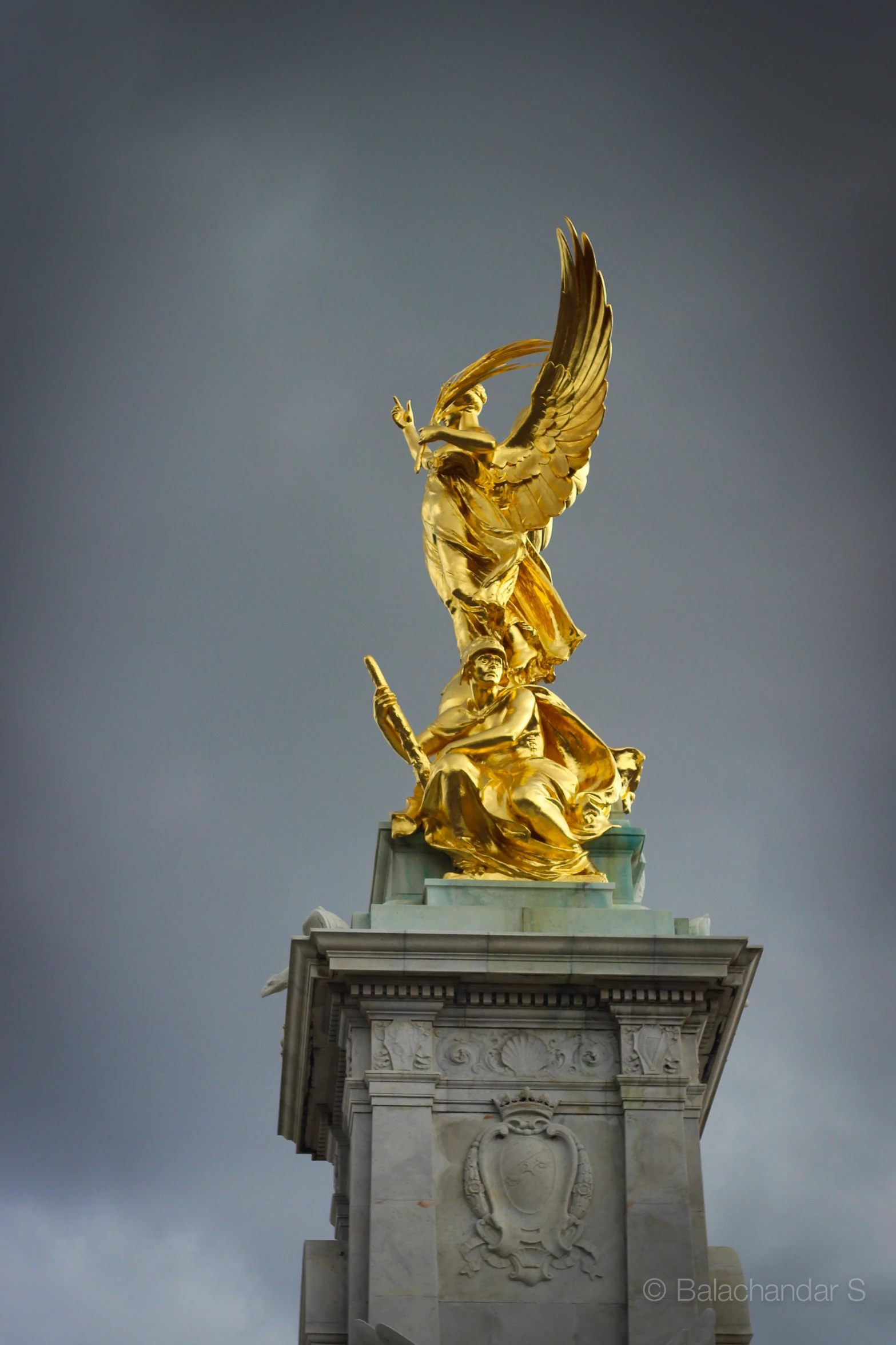 a golden statue atop the top of a white building