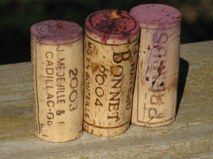 three old used wine corks on a table
