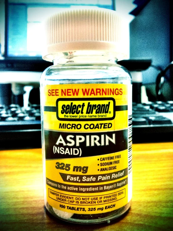 a bottle of aspirin sits next to a keyboard