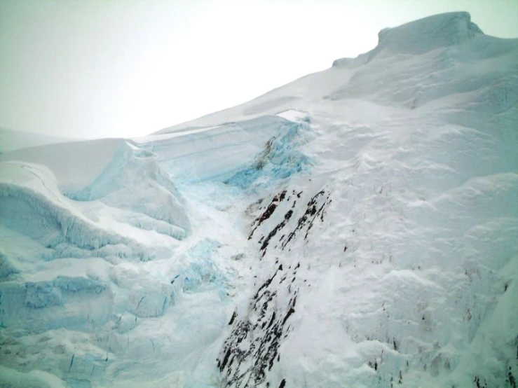 a large snow covered mountain side with snow on the ground