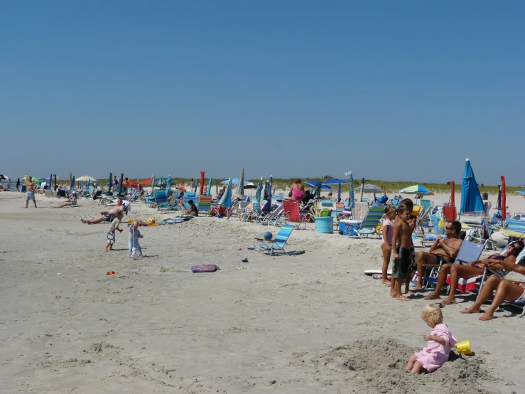 people sitting in chairs on a sandy beach