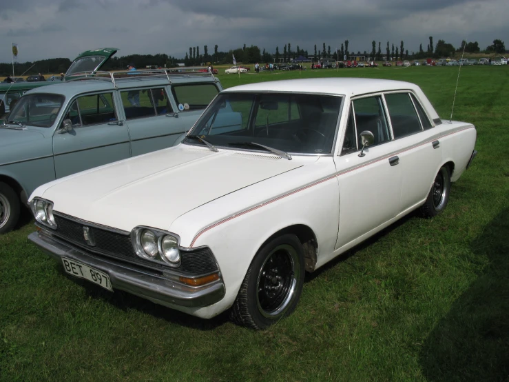 two white cars that are sitting in the grass