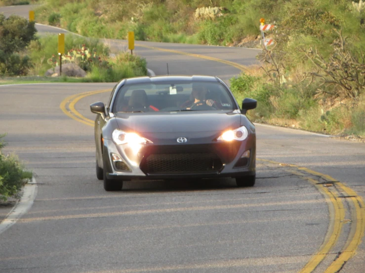 the scion is driving on the road with people in the front of it