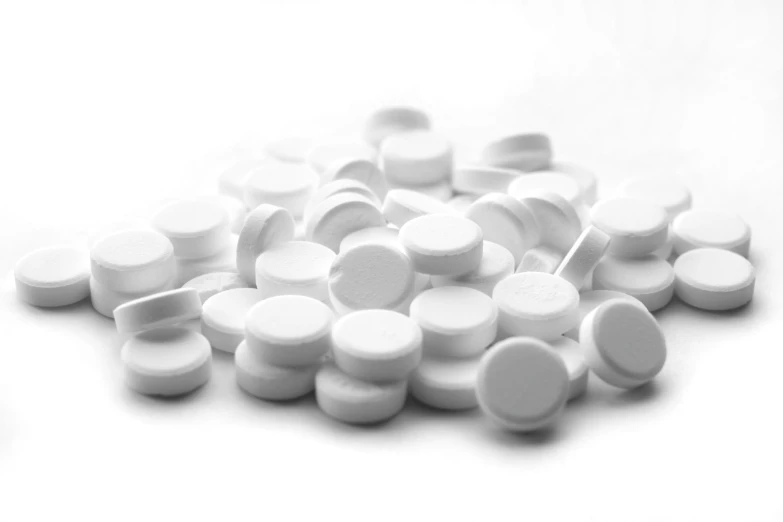 many white round pills scattered on a white surface