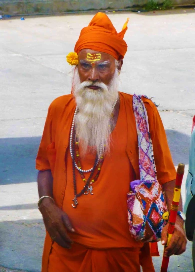 an old man in orange and white with a large beard