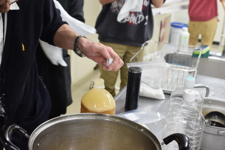 a person uses some type of liquid to pour water in a saucepan