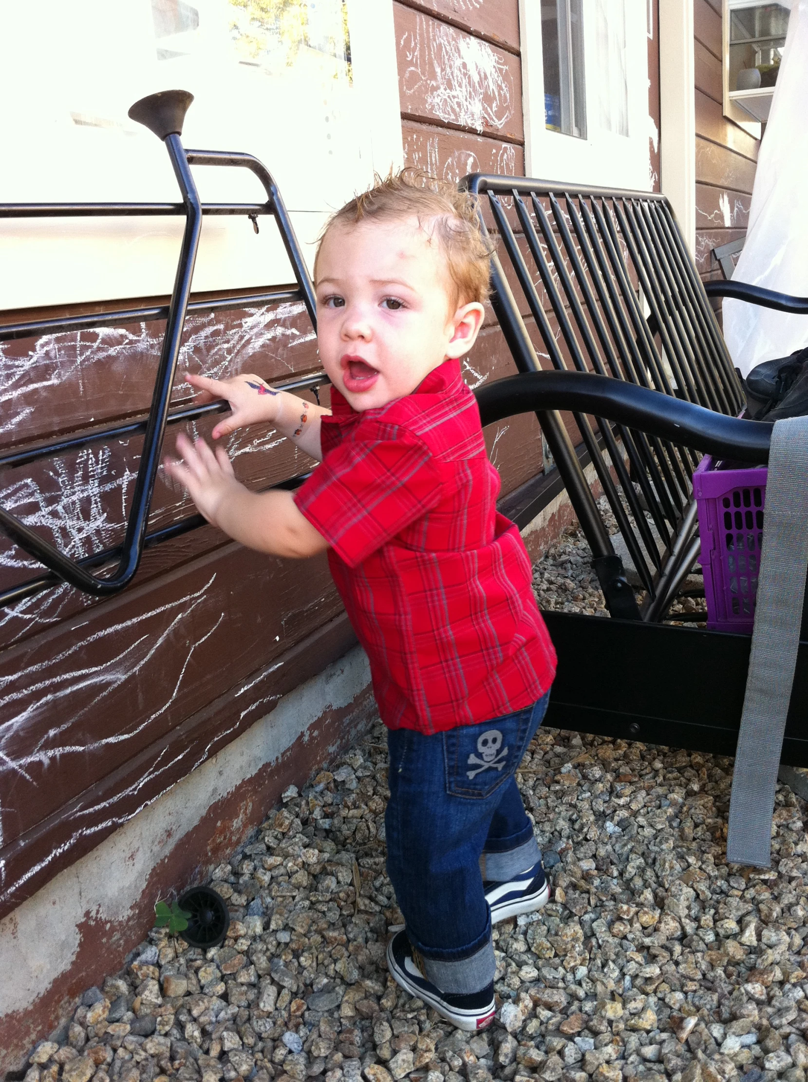 a small child reaching over a bench to touch soing