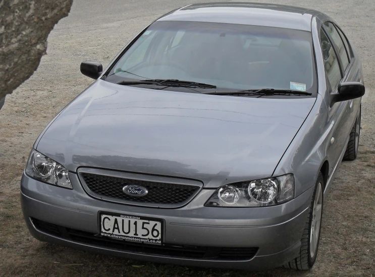 a silver car parked in front of a tree