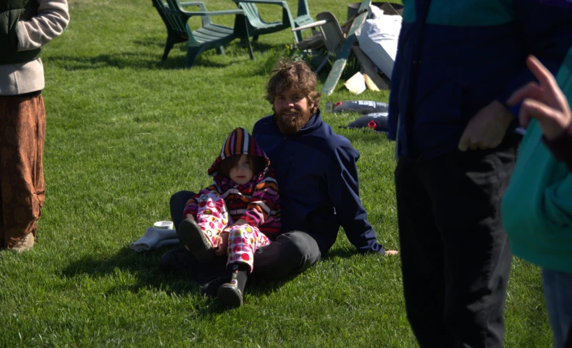 two people on the ground with one of them holding a little girl