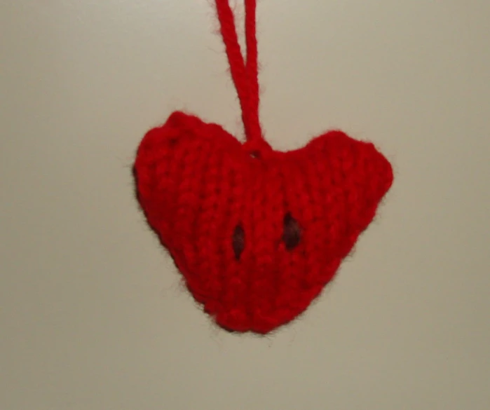 a red heart shaped decoration hangs from a wall