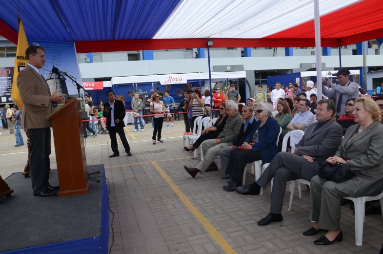 many people are sitting down and the man is giving a speech