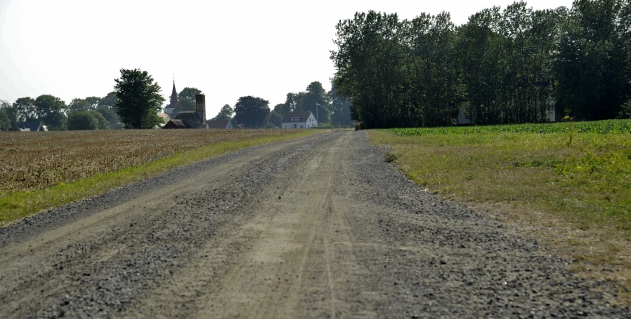 a small dirt road with some trees in the background