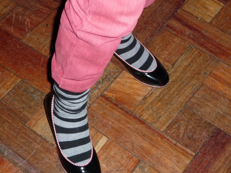 a woman standing on top of a wooden floor wearing striped socks