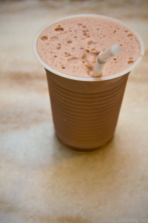 a drink with brown substance in it is sitting on the table