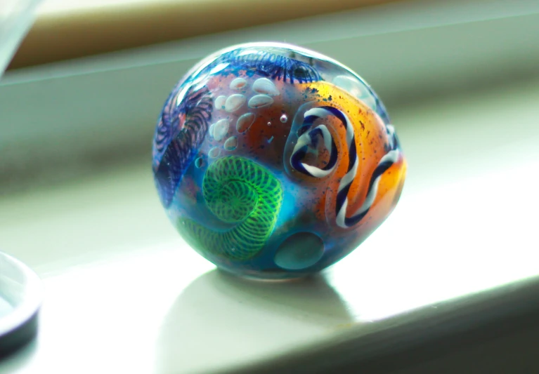 there is an ornamental painted glass decoration sitting on a window sill