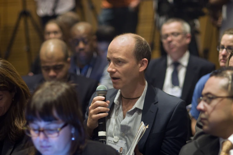 a man in business attire and speaking into a microphone