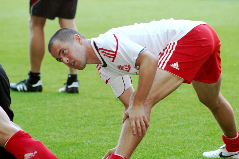 a man with his head down bends over to touch his knee