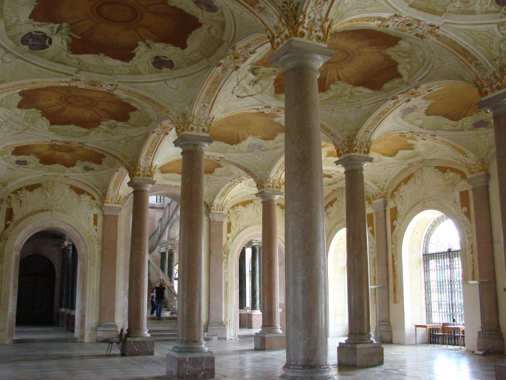a stone and stucco ballroom has multiple columns with intricate ceilings