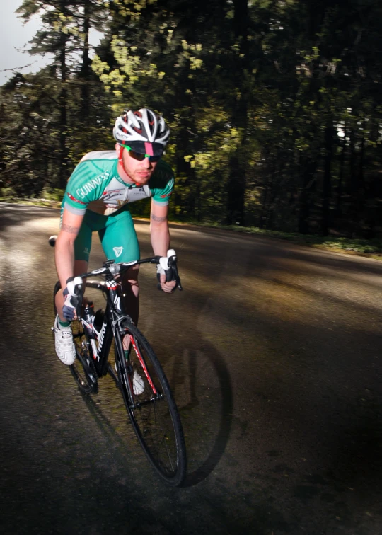 man riding bike on paved road near wooded area