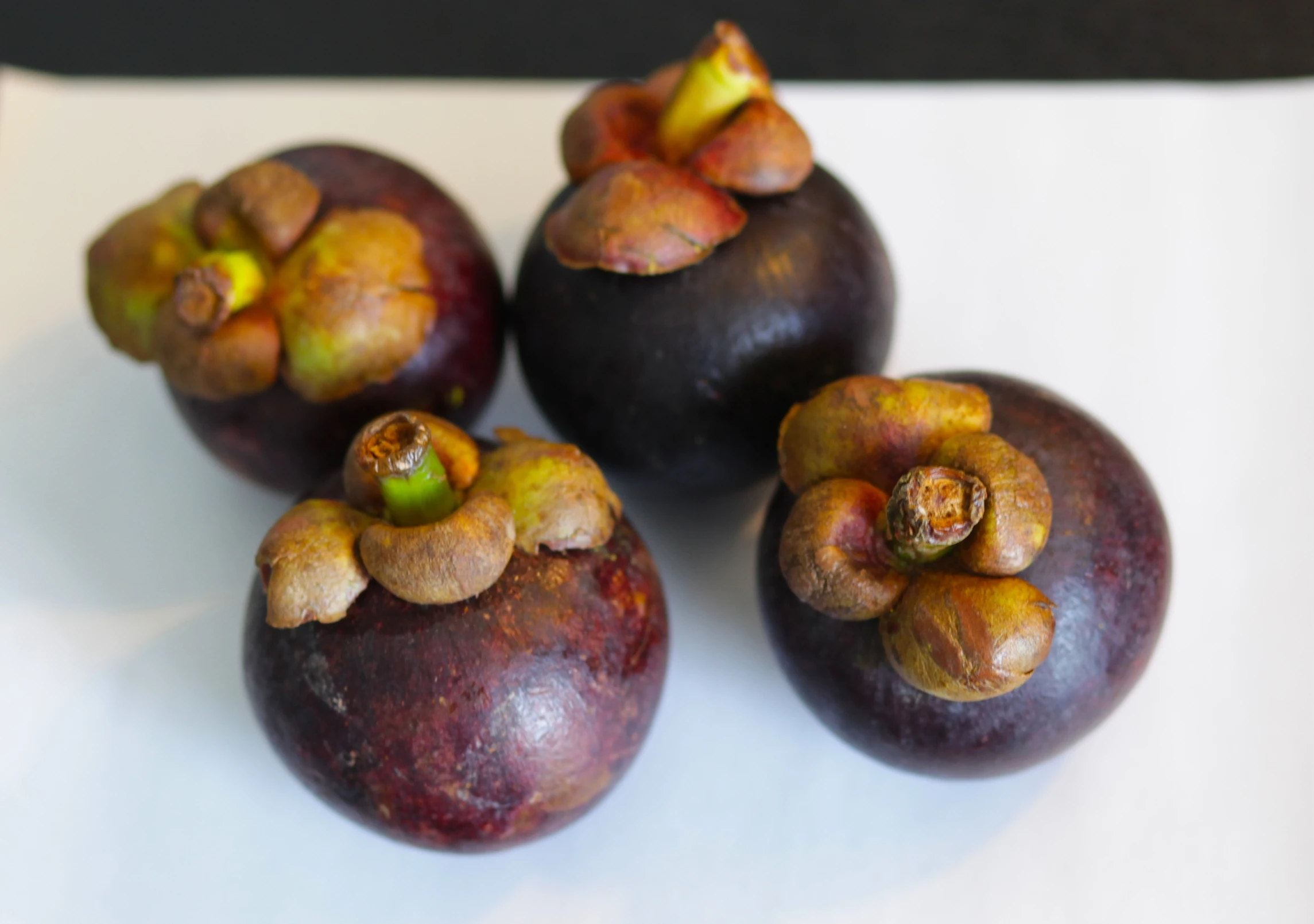 a group of four plums on a white table