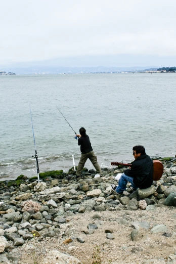 there are some men fishing on the lake shore