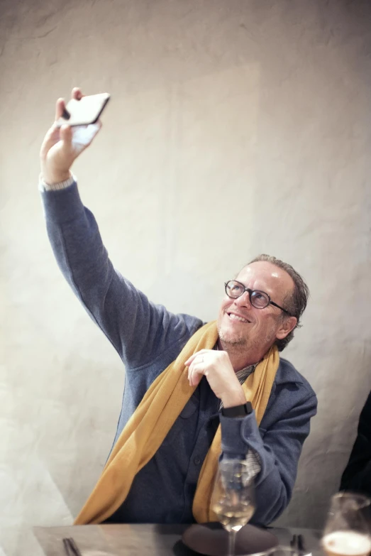 man wearing glasses, holding up his cellphone at the table