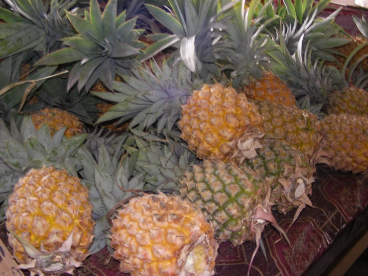 some pineapples on a table near other fruits