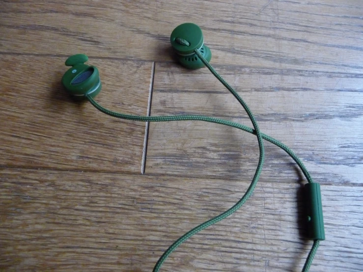 green headphones laying on a wooden floor