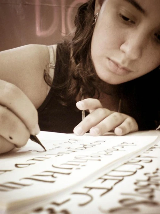 a woman is writing on paper with a pen