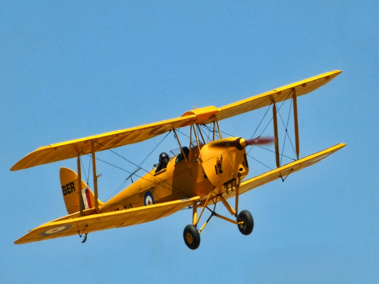 an old yellow plane in the blue sky