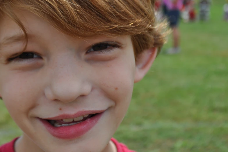 a close up of a child smiling in a field