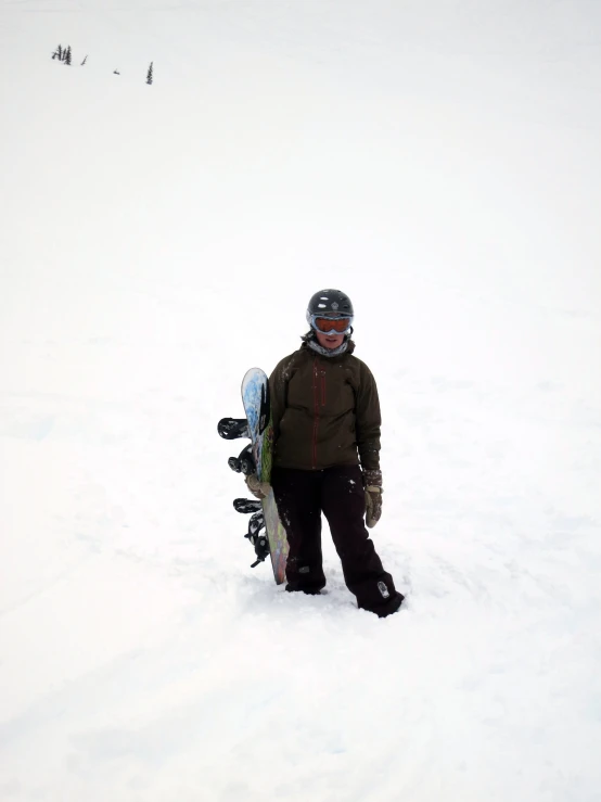 man standing in the snow holding a snowboard