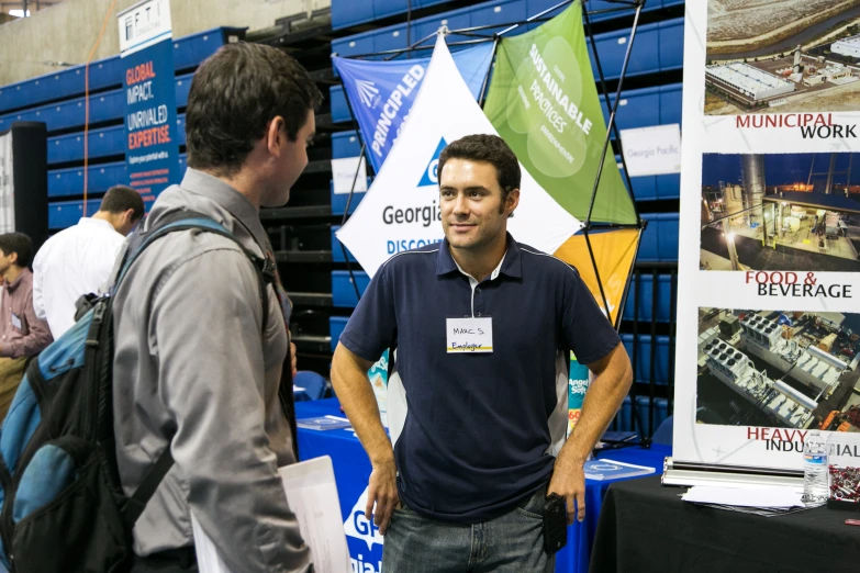 two men standing next to each other in front of posters