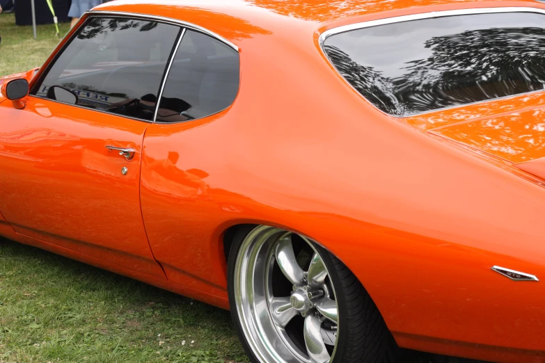 a large orange car parked on top of a grass covered field