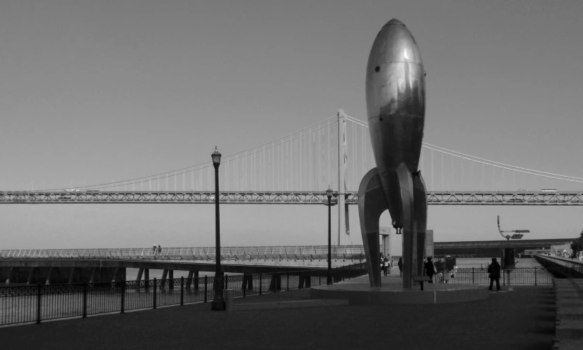 a airplane shaped sculpture in front of a bridge