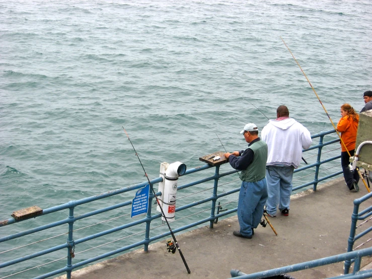 two men fishing on the pier while others watch