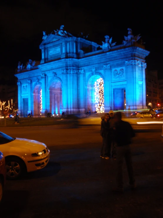 people gathered in front of an ornate lit building