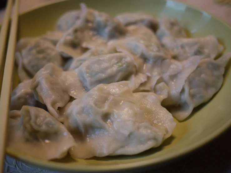 a plate of dumplings with chop sticks in it