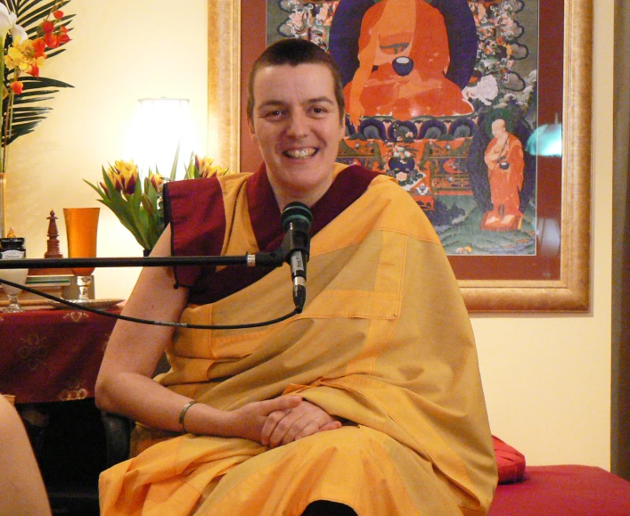 a man smiling while wearing an orange and yellow sarong