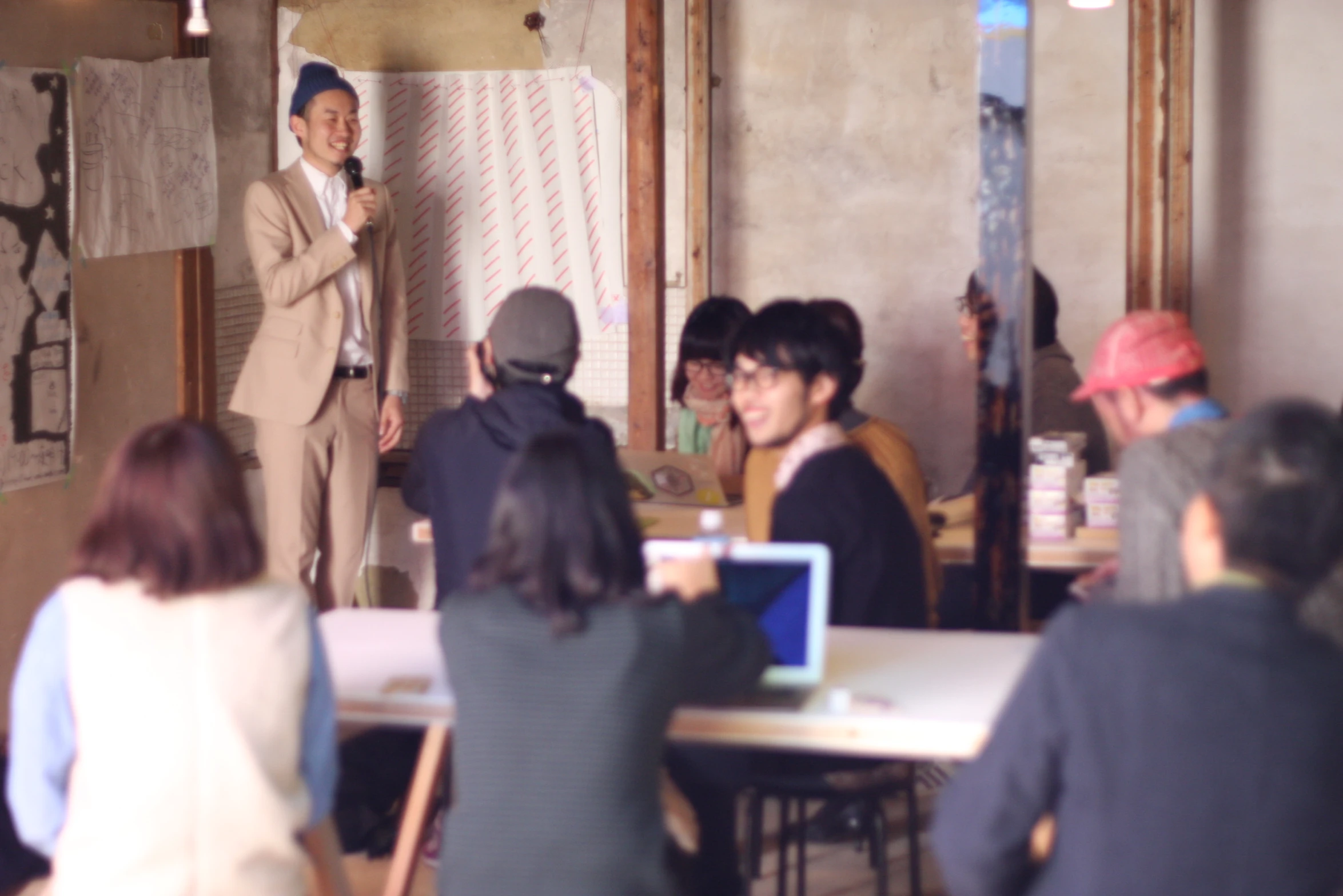 people at tables with laptops and a man standing on the screen