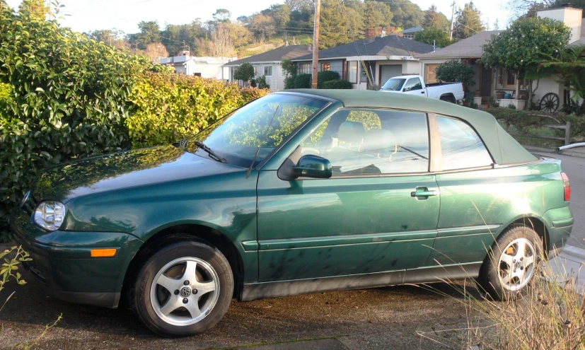 the car is parked in the driveway next to some bushes