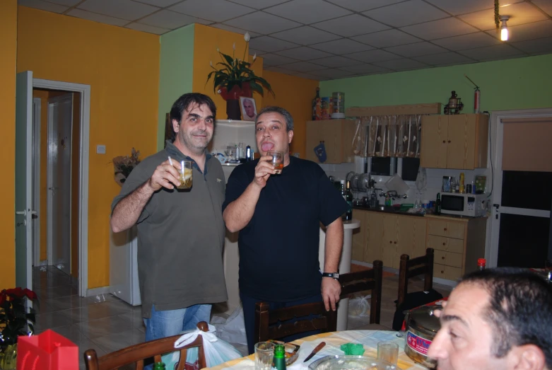 two men standing near each other with drinks in front of them